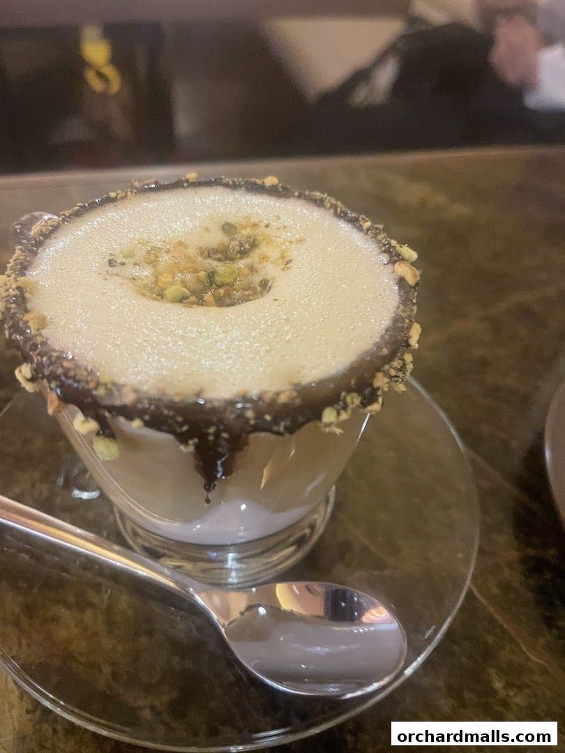 A close-up of a dessert drink with chocolate rim and pistachio topping.