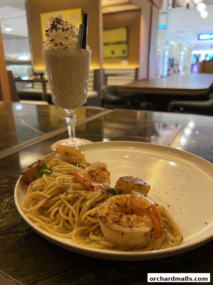A plate of shrimp pasta and a milkshake with whipped cream and sprinkles.
