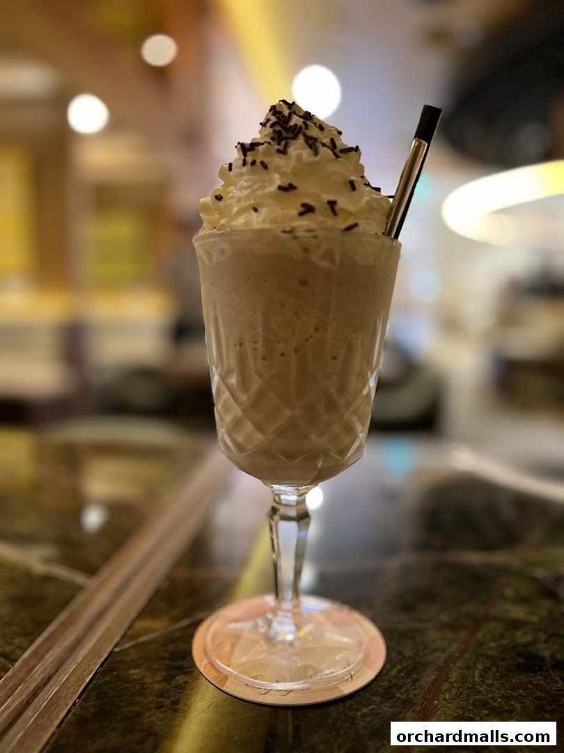 A decadent milkshake topped with whipped cream and chocolate sprinkles in a crystal glass.
