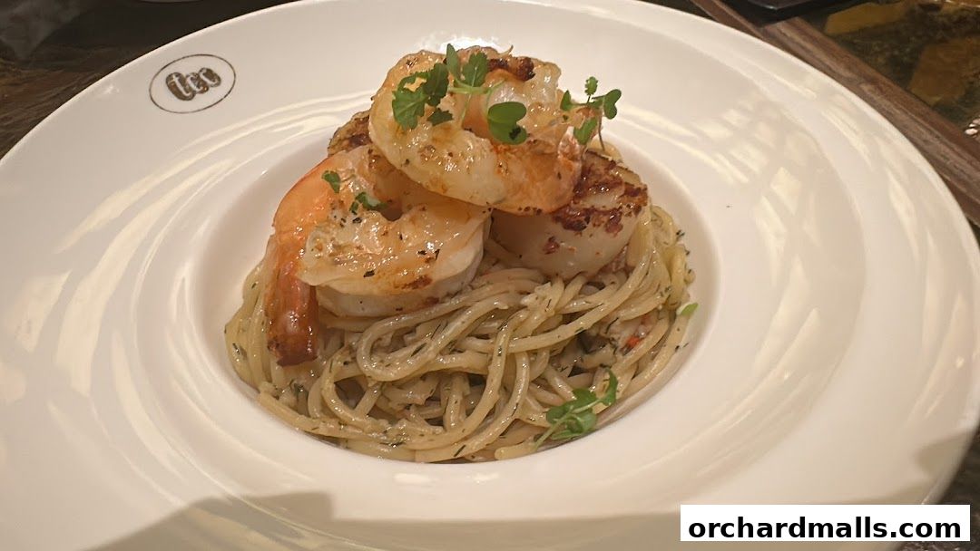 A white plate of spaghetti with shrimp and scallops, garnished with herbs.