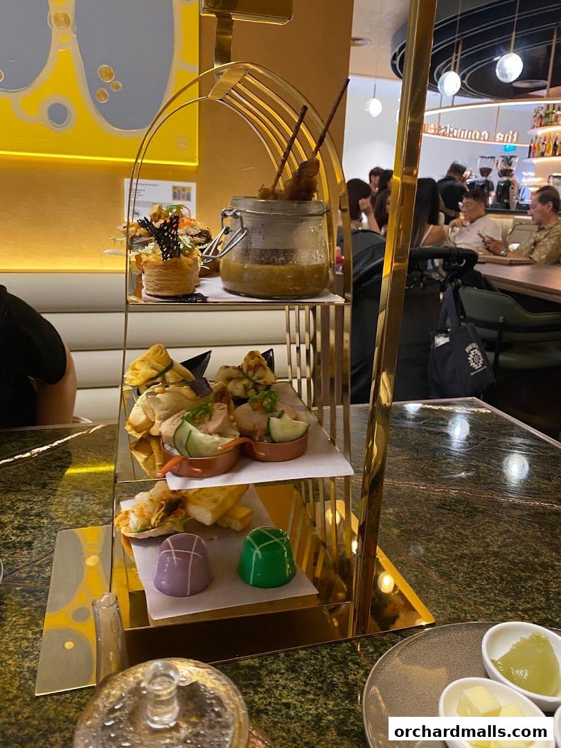 A tiered stand displays a selection of savory and sweet treats, including skewers and pastries.
