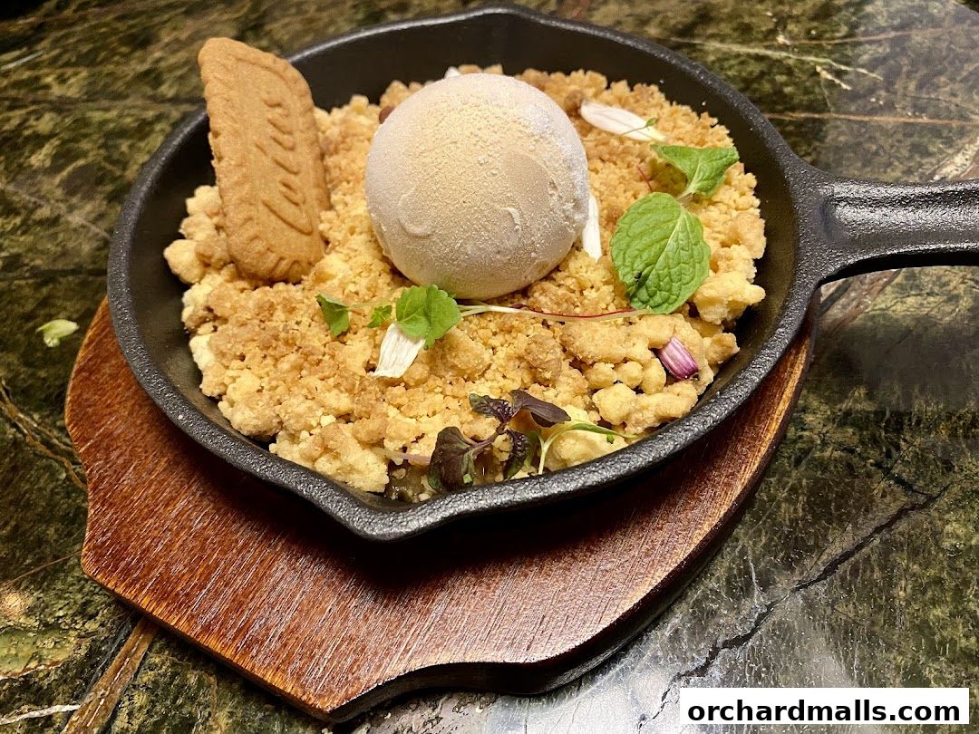 A warm dessert served in a cast-iron skillet with ice cream and a biscuit.