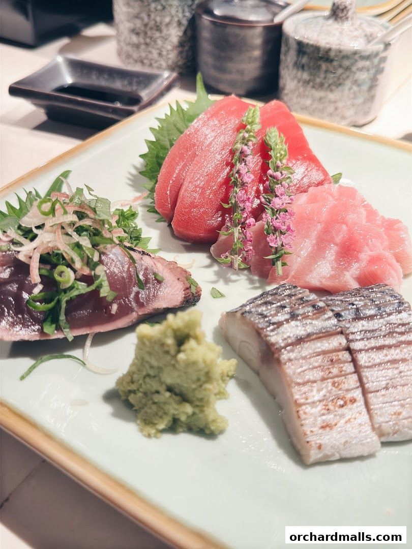 A plate of assorted sashimi with wasabi and garnishes, beautifully presented.