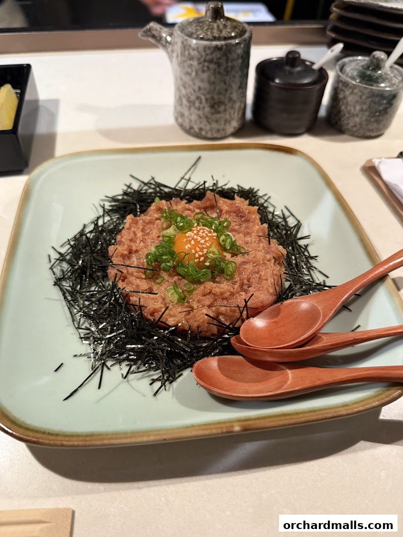 A finely chopped tuna dish served with seaweed, egg yolk, and green onions.