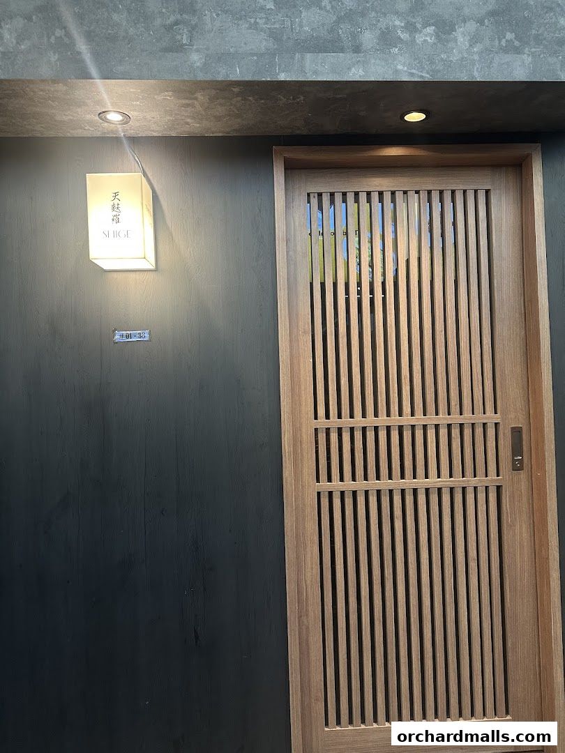 The entrance of Tempura SHIGE, featuring a wooden slatted door and a lit sign.