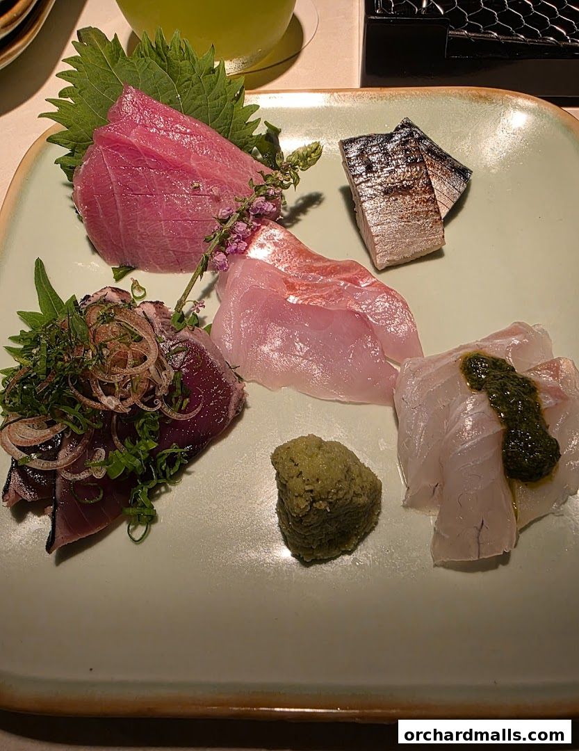 A plate of assorted sashimi with wasabi and garnishes.