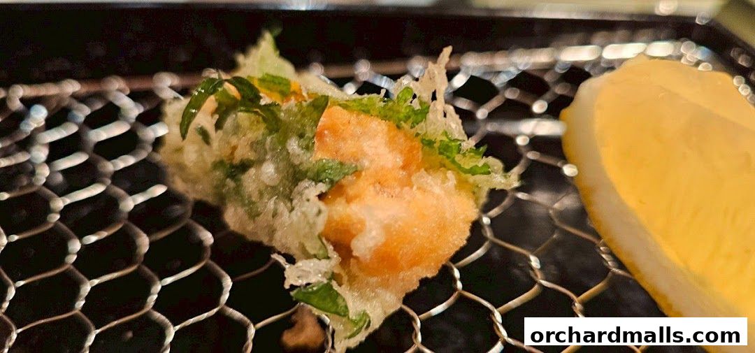A close-up of a crispy tempura dish with green herbs on a wire rack.