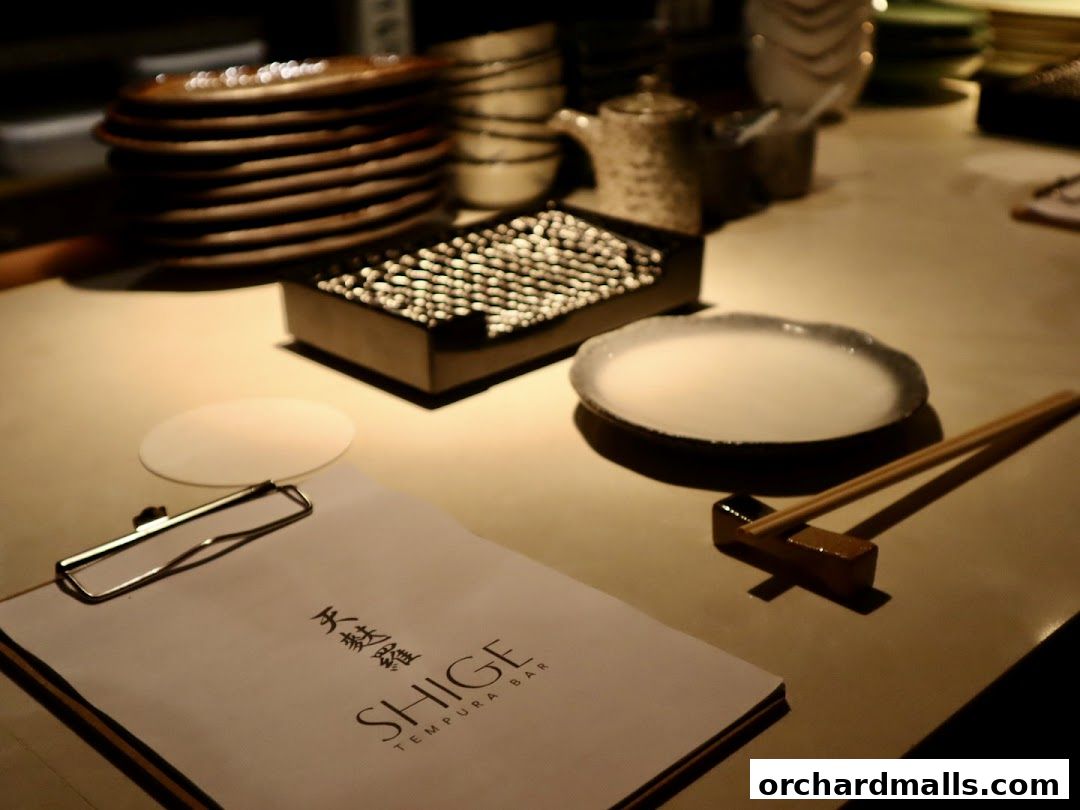 A table setting at Tempura SHIGE with a menu, chopsticks, and a dipping sauce.