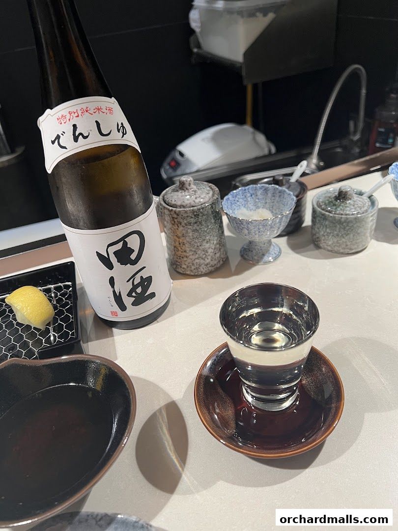 A bottle of sake, a sake cup, and small dishes are arranged on a table.