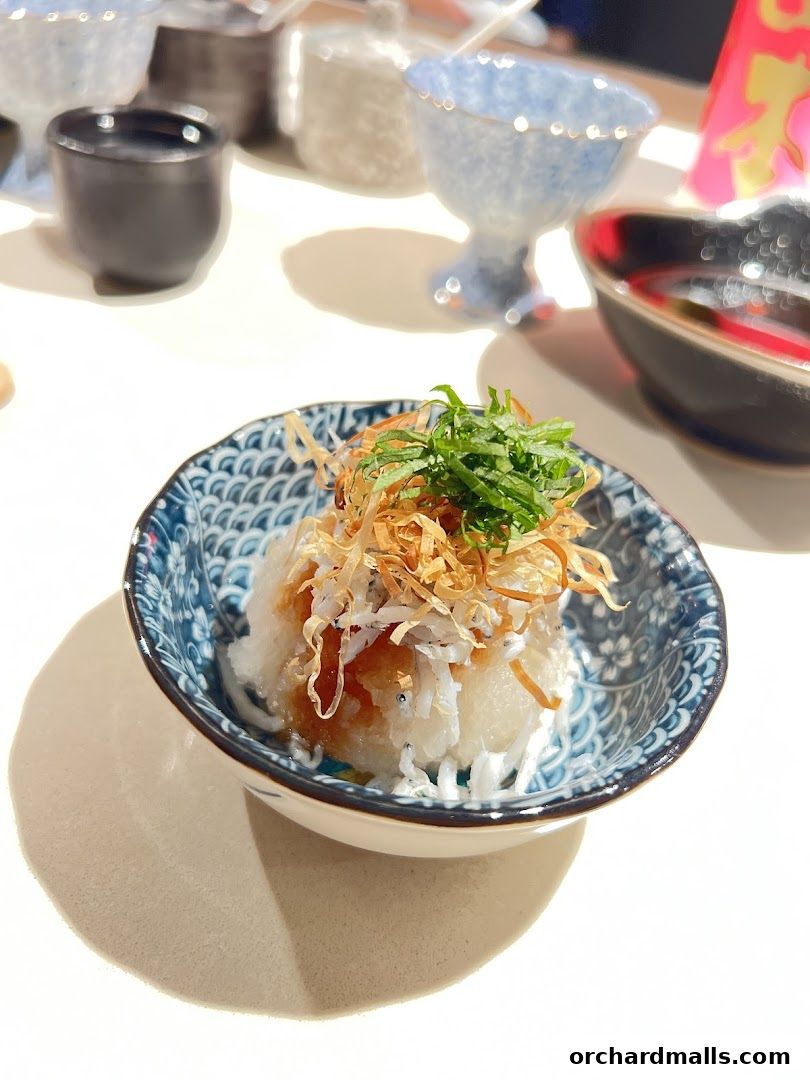 A small bowl of grated daikon radish topped with shirasu and bonito flakes.