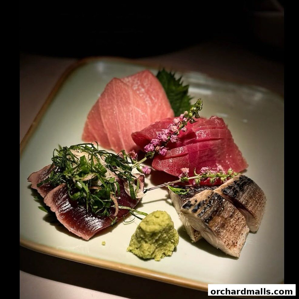 A plate of assorted sashimi with wasabi and garnishes, beautifully presented.