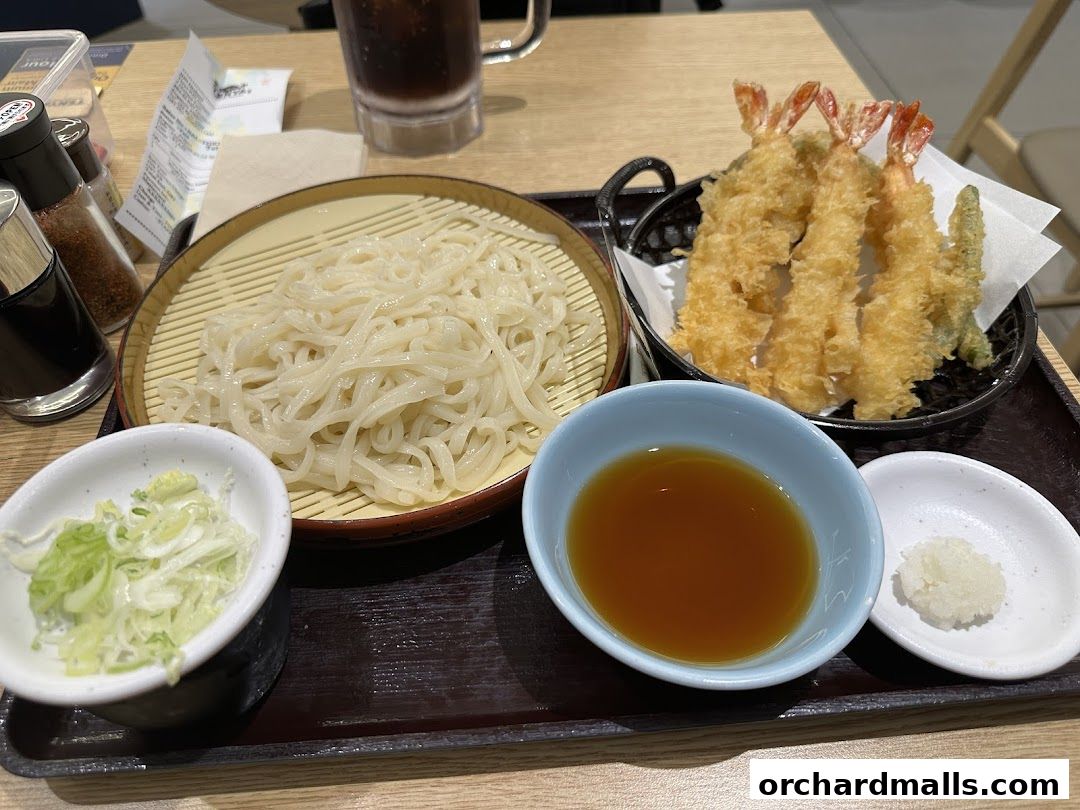 A delicious meal of tempura shrimp and soba noodles with dipping sauce and condiments.