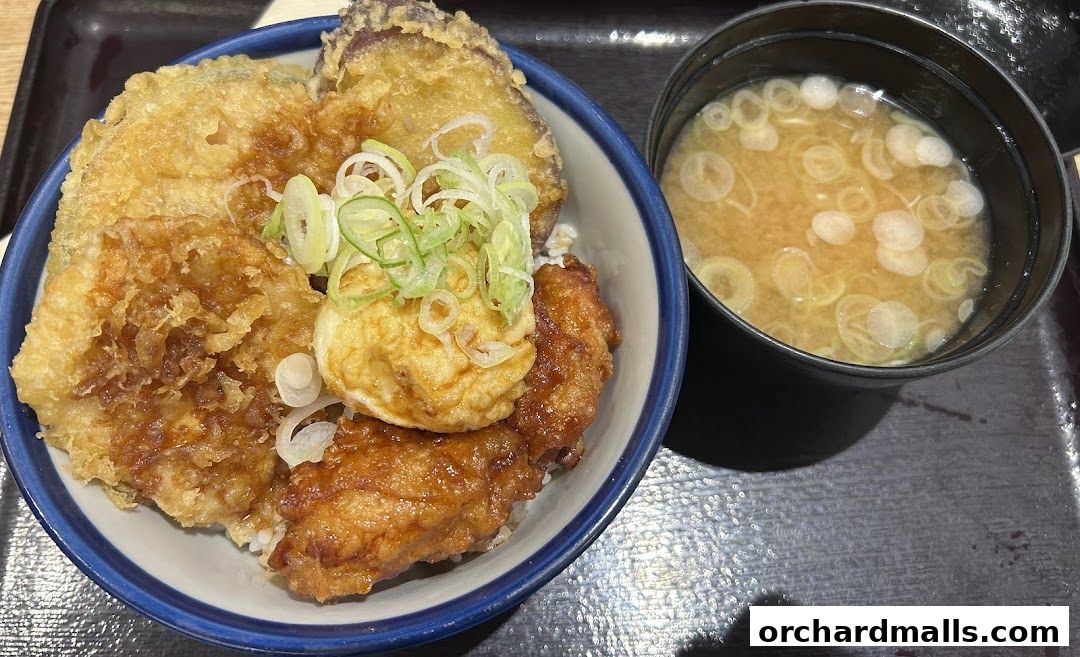 A close-up of a Japanese rice bowl with tempura and a side of miso soup.