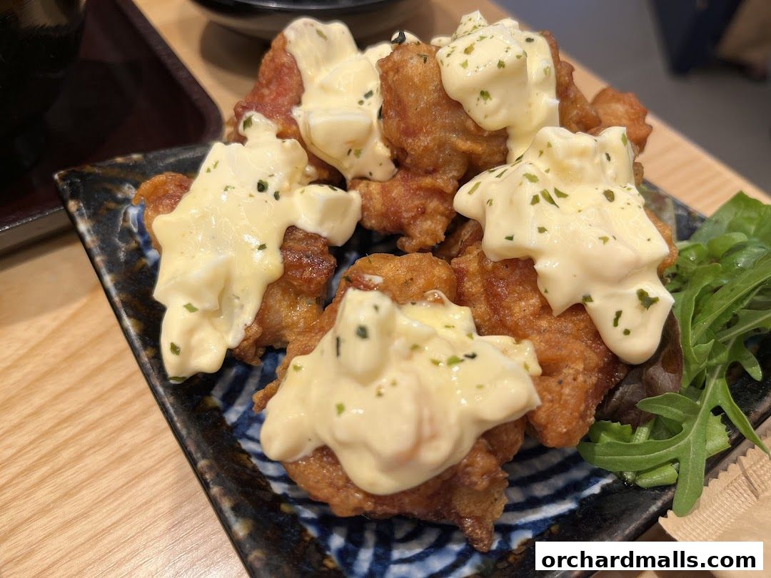 A close-up shot of crispy fried chicken pieces topped with creamy sauce and garnished with herbs.