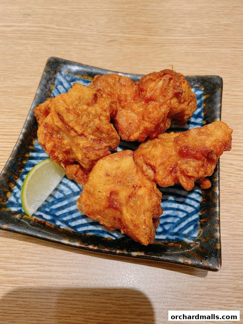 A plate of crispy fried chicken pieces with a lime wedge on a patterned blue and white plate.