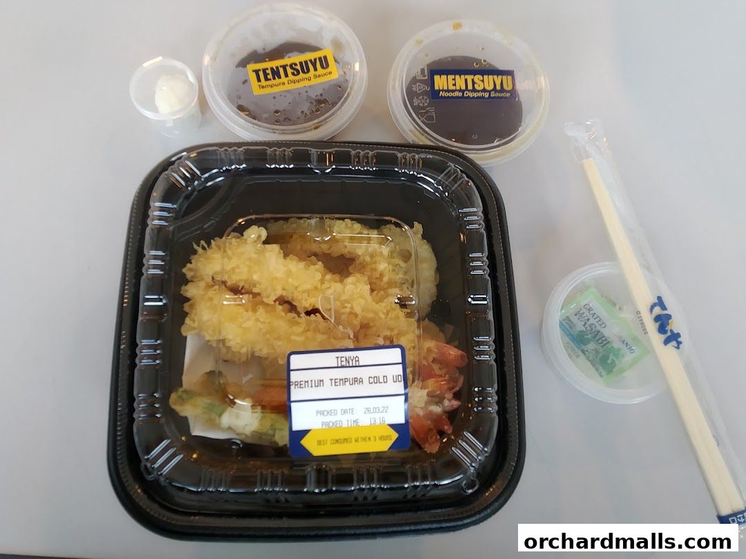 A takeout container of premium tempura with dipping sauces and chopsticks.