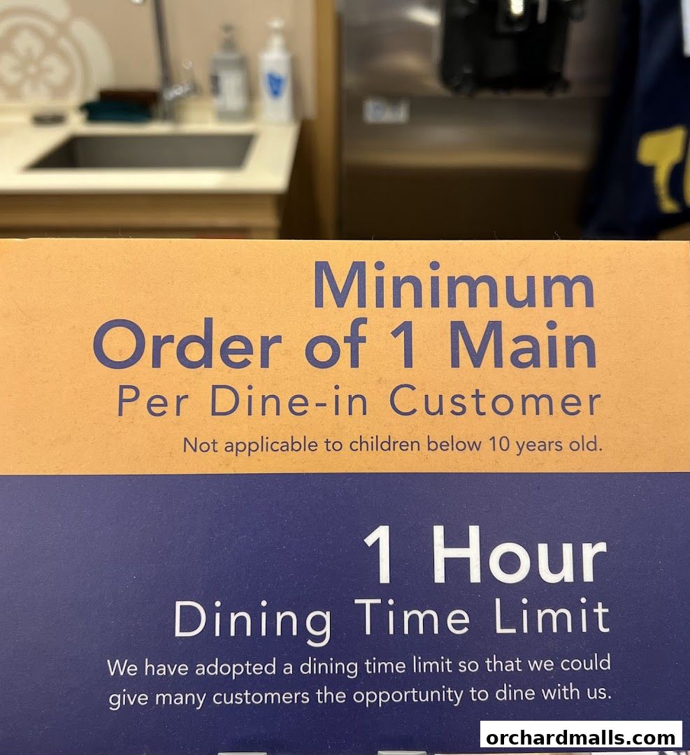 A sign indicating a minimum order of 1 main per dine-in customer and a 1-hour dining time limit.