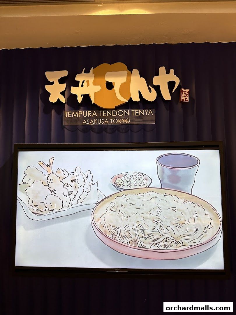A digital display showcasing a Japanese meal with tempura and noodles, with the restaurant's logo above.