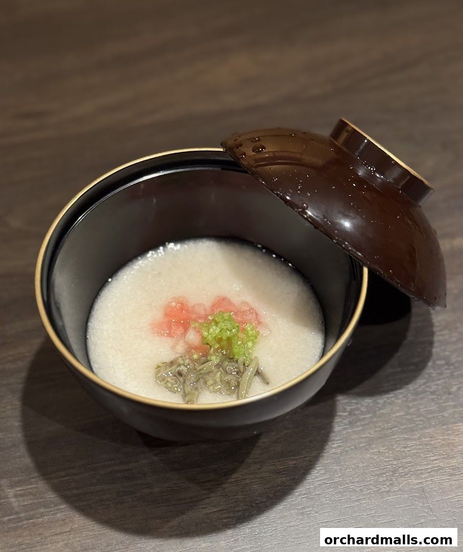 A close-up of a Japanese dish in a dark bowl with a lid.