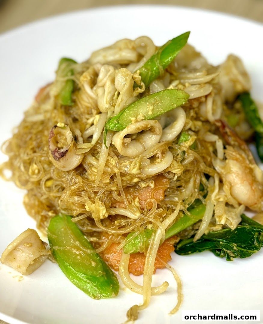 A close-up shot of a delicious Thai noodle dish with seafood and vegetables.