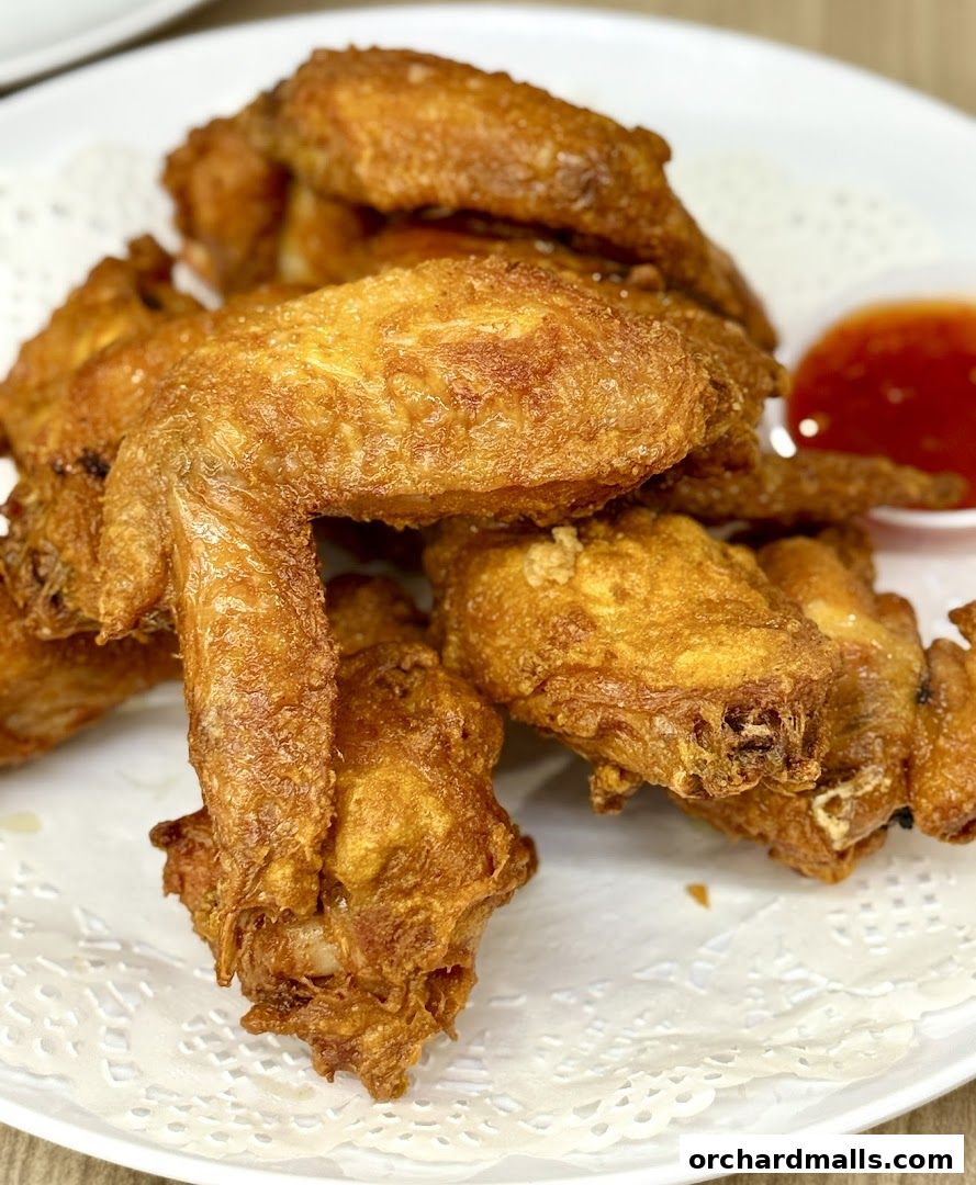 A plate of crispy fried chicken wings served with a side of sweet chili sauce.