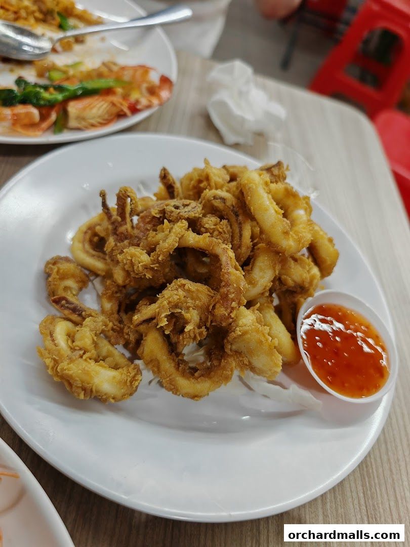 A plate of crispy fried calamari served with a side of sweet chili sauce.