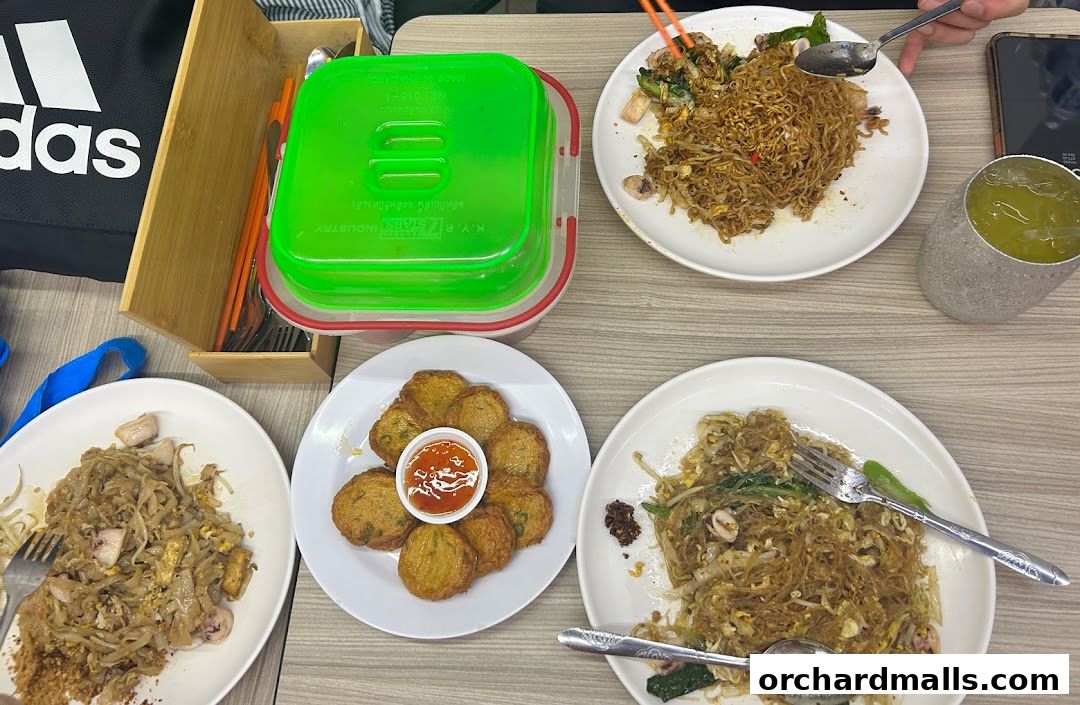 A table laden with various Thai dishes, including noodles and fish cakes, ready to be enjoyed.