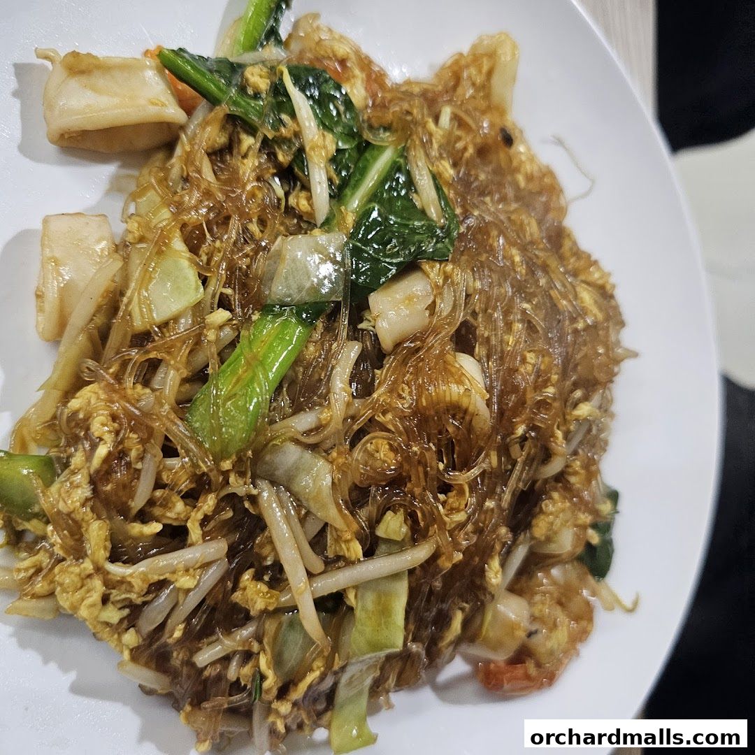 A close-up shot of a delicious Thai noodle dish with vegetables and seafood.