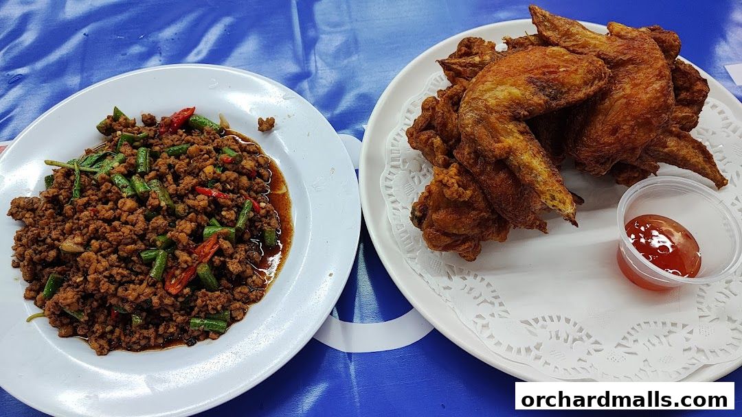 A plate of minced meat with green beans and chili next to fried chicken wings with dipping sauce.
