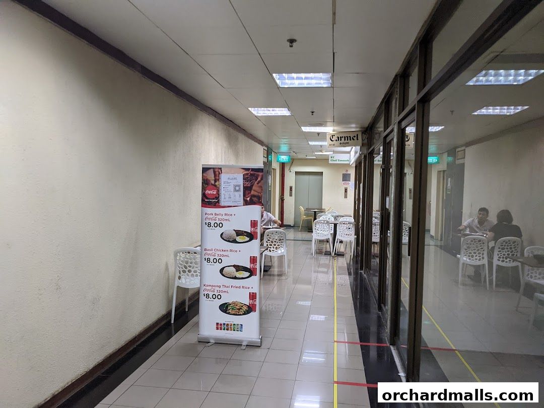 A promotional banner for Thai cuisine is displayed in a mall corridor.