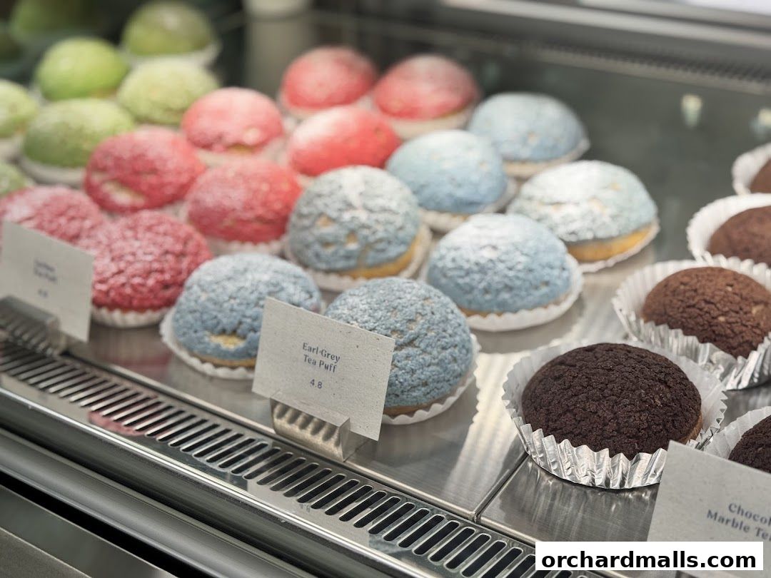 A display case filled with colorful cream puffs in various flavors.