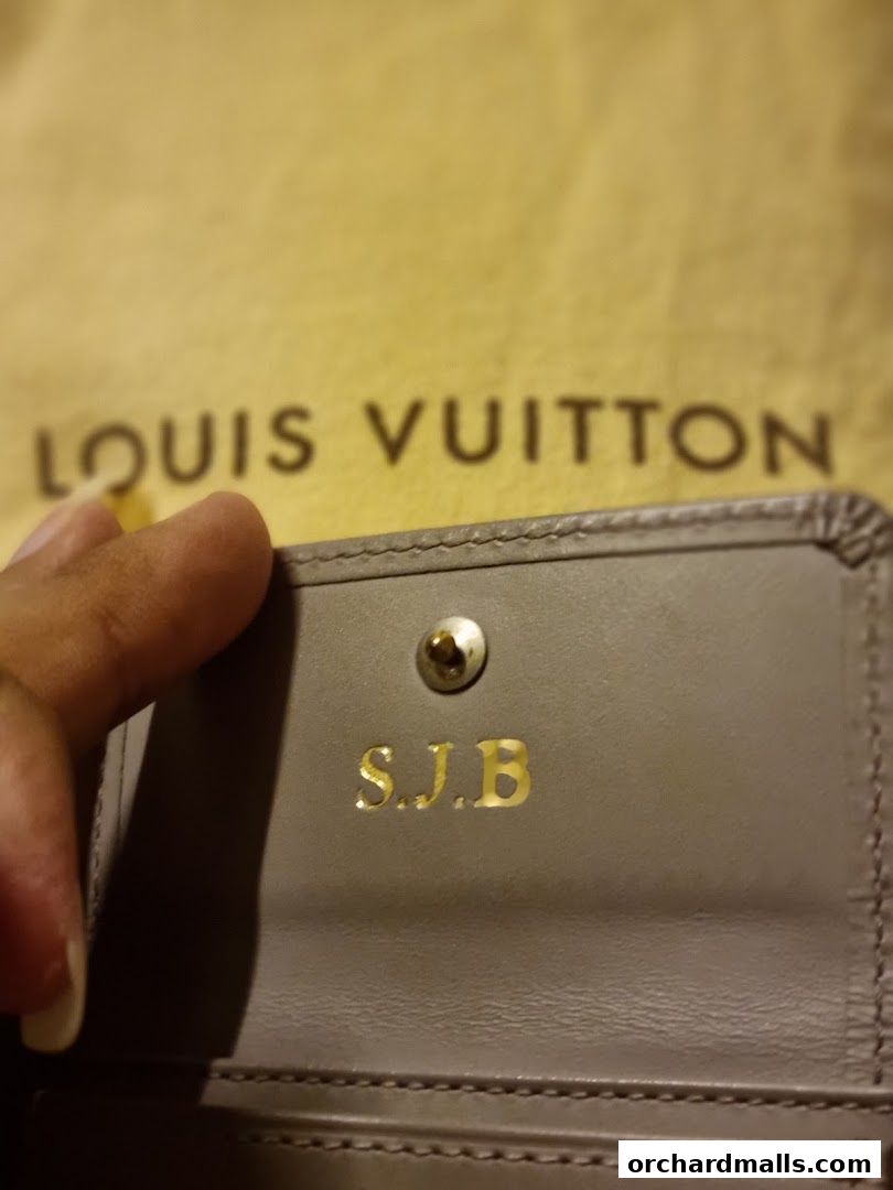 Close-up of a personalized Louis Vuitton wallet with initials S.J.B.