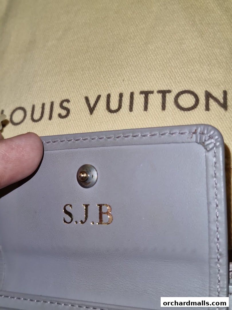 Close-up of a personalized Louis Vuitton wallet with initials S.J.B.