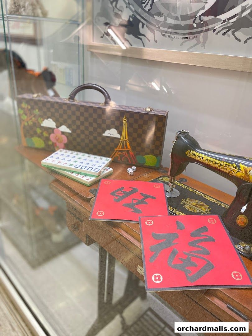 A vintage sewing machine displays decorative items including a checkered suitcase and red calligraphy.