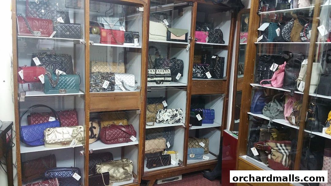 A display of various designer handbags in glass-fronted cabinets.