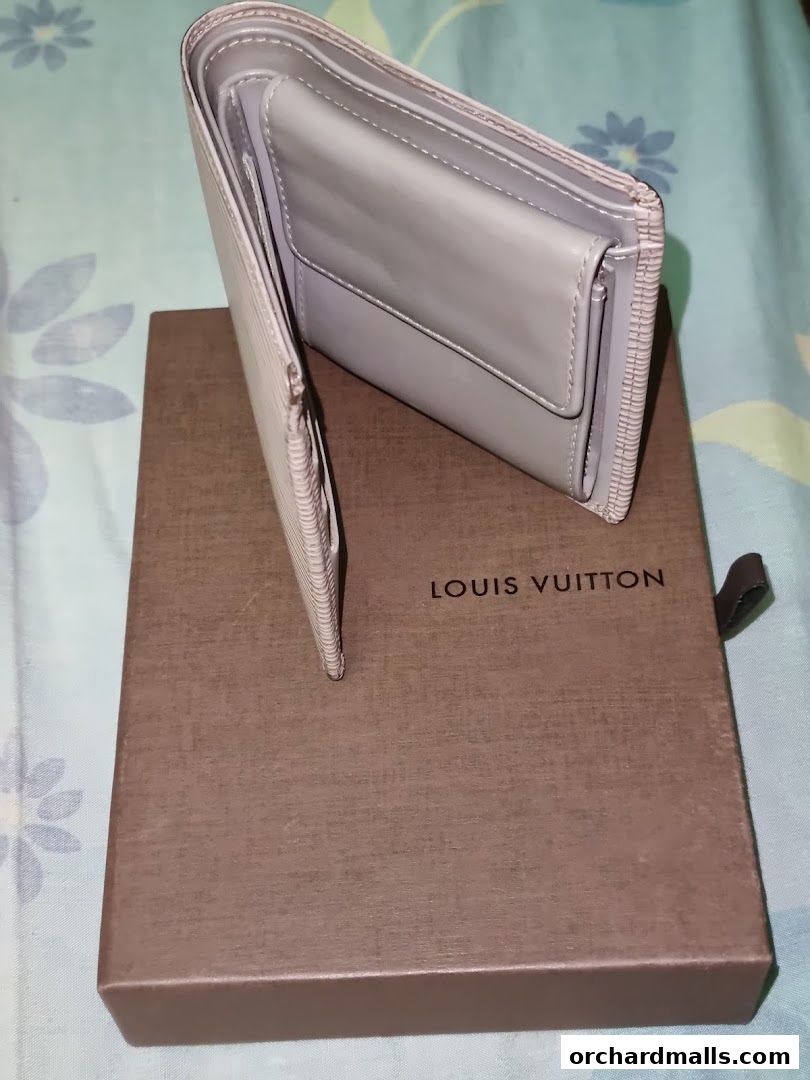 A light grey Louis Vuitton wallet is displayed on its branded box.