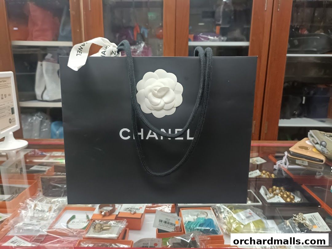 A black Chanel shopping bag with a white camellia flower and rope handles.