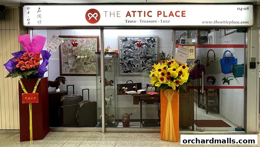 The Attic Place shop front with floral arrangements, luggage, and displayed luxury items.