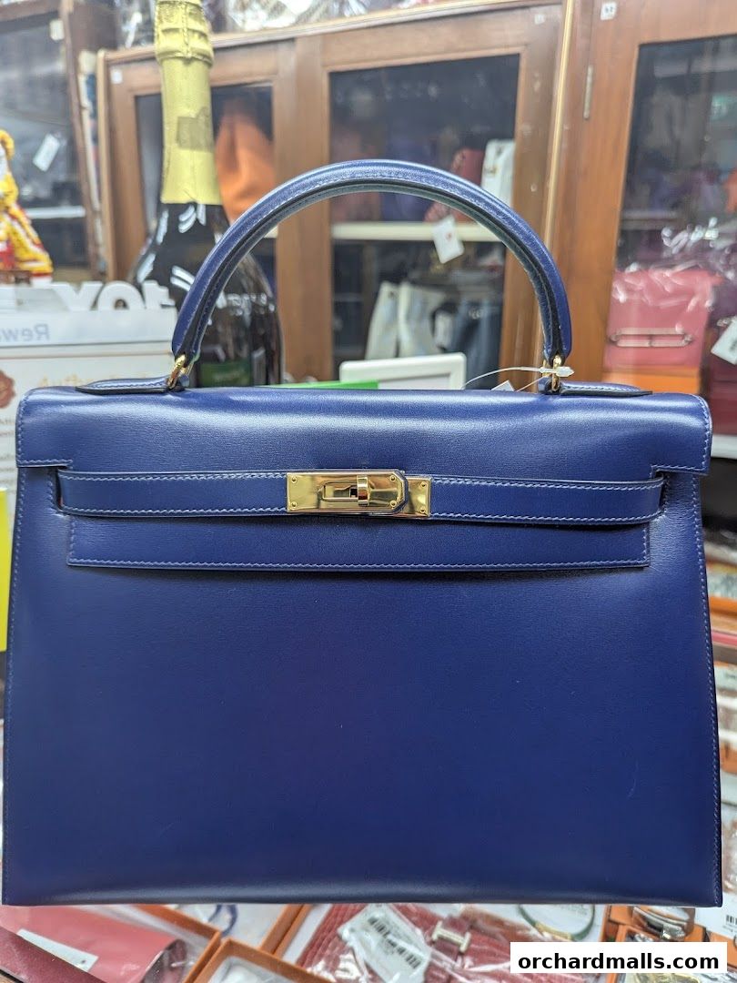 A close-up of a luxurious blue handbag with gold hardware, displayed in a shop.