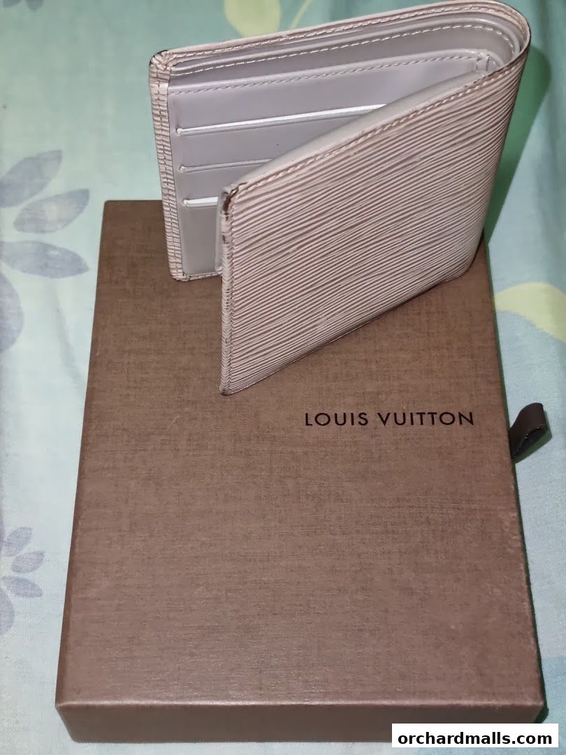 A light-colored Louis Vuitton wallet is displayed on its branded box.