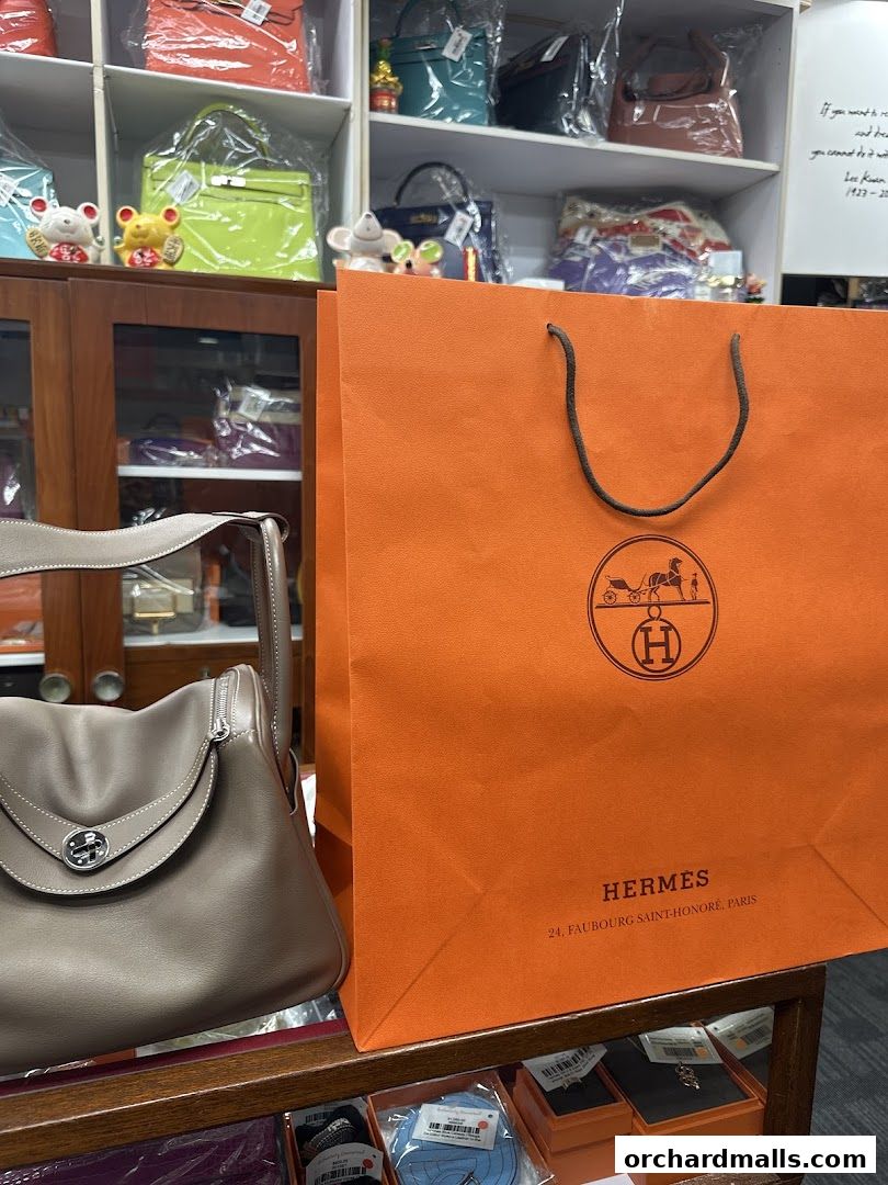 A luxury handbag and an orange shopping bag with Hermes branding.