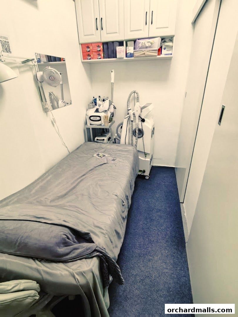 A treatment room with a massage bed, beauty equipment, and storage cabinets.