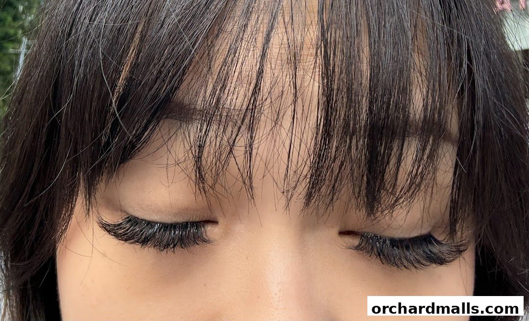 Close-up of a person's eyes with dramatic, voluminous false eyelashes and bangs.