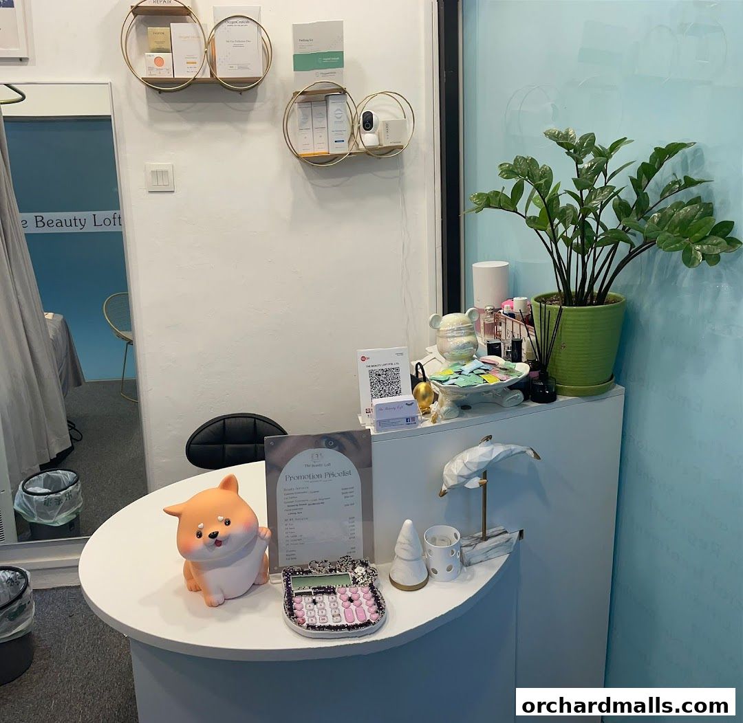 A reception desk at The Beauty Loft with a pricelist, calculator, and decorative items.