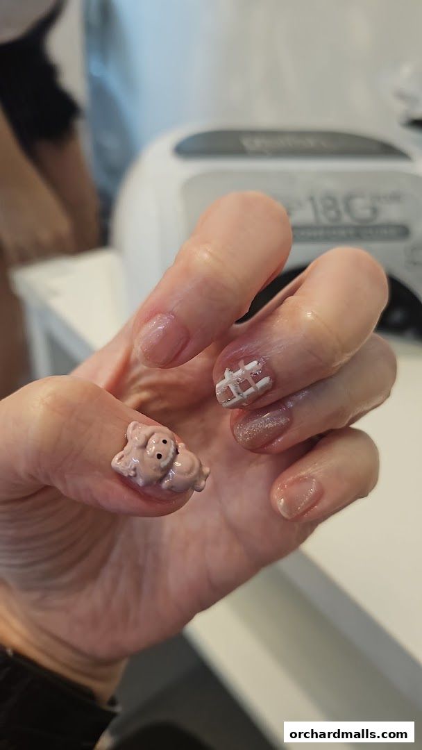 A hand with a cute 3D pig nail art and a checkered design.
