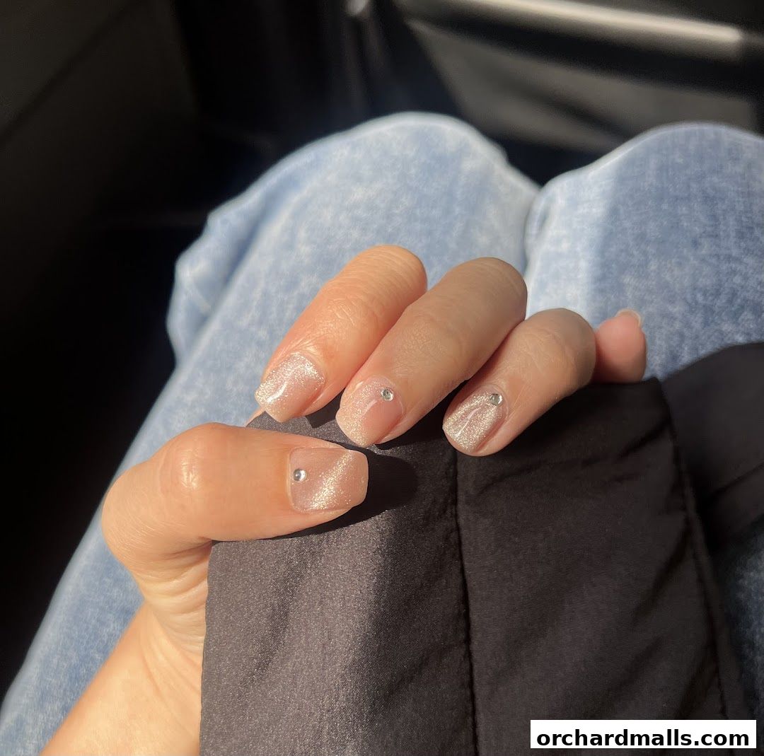 A hand with elegant, sparkling nails adorned with small rhinestones.