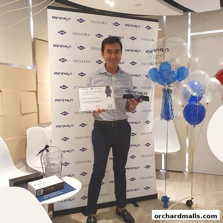 Man holding a certificate and award with balloons and clinic branding in the background.