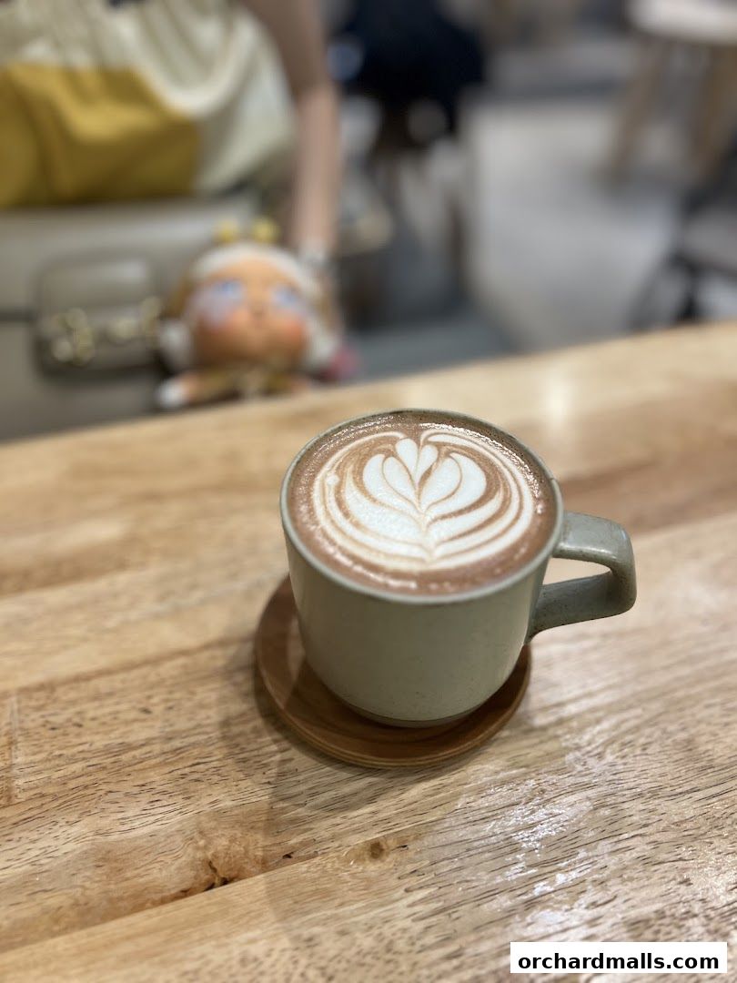 A close-up of a latte with intricate art on a wooden table.