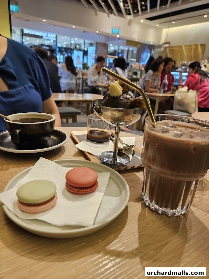 A table with coffee, macarons, ice cream, and a chocolate drink.