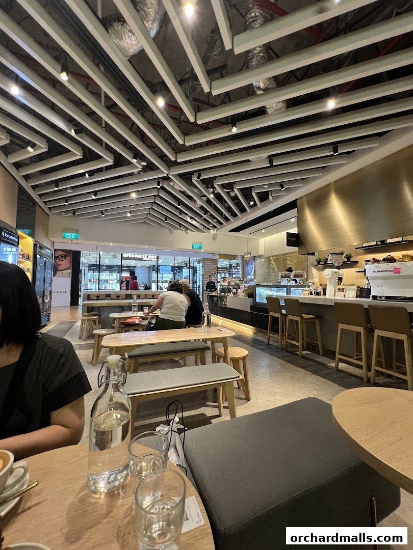 Interior view of a modern cafe with wooden tables, benches, and a counter.